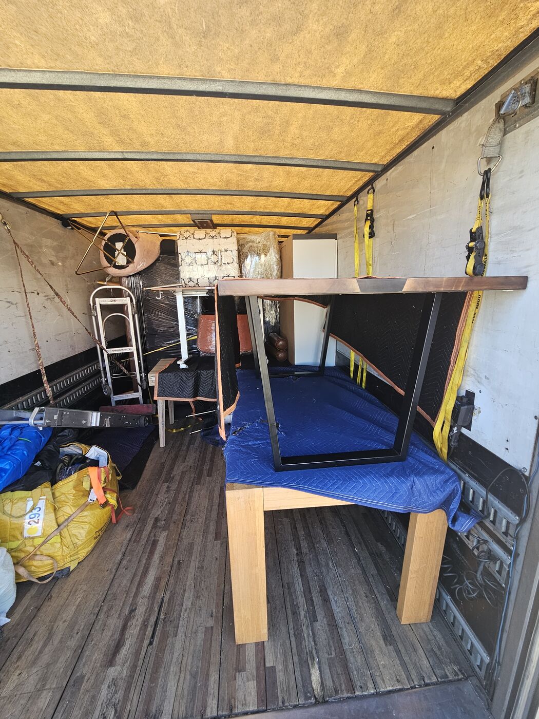 Dining table padded with moving blankets and loaded legs-up in a box truck