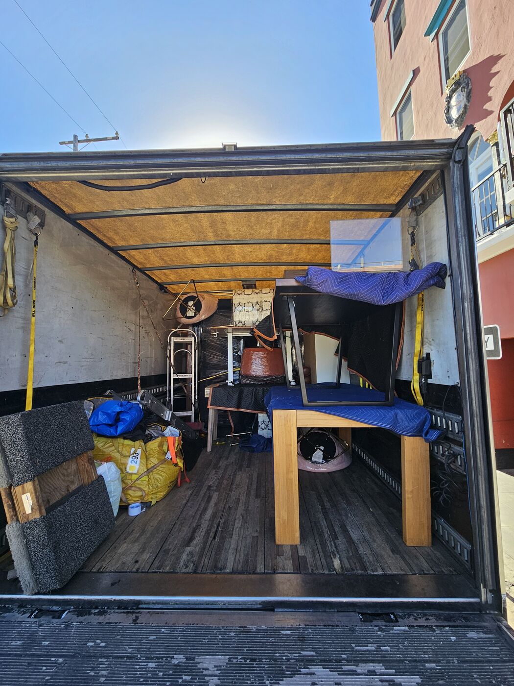 Tiered box truck load with furniture stacked and secured by ratchet straps