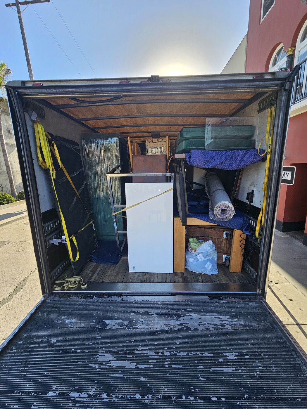 Box truck packed floor to ceiling with strapped furniture, rugs, and appliances