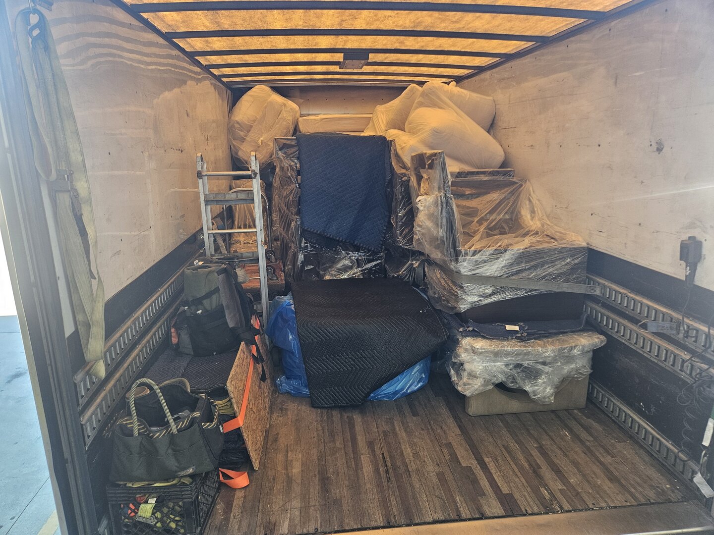 Well-organized truck interior showing professional furniture packing with E-track system and moving equipment